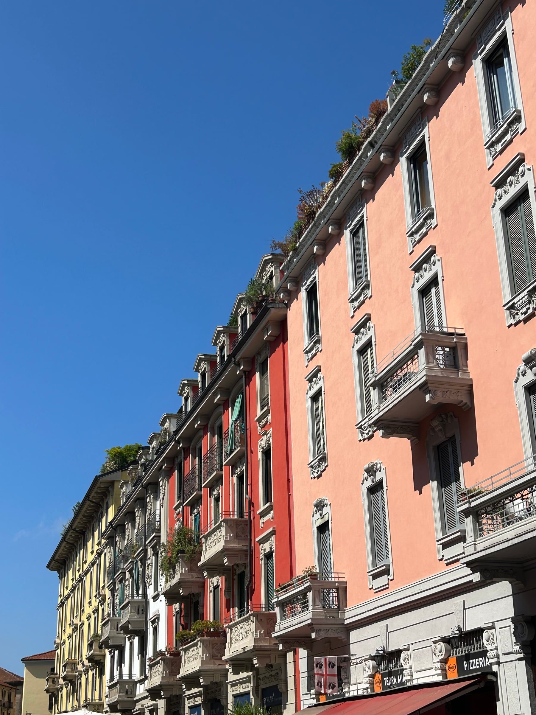 The colorful facades of the houses on via Sebenico, in Isola, seen from the opposite sidewalk