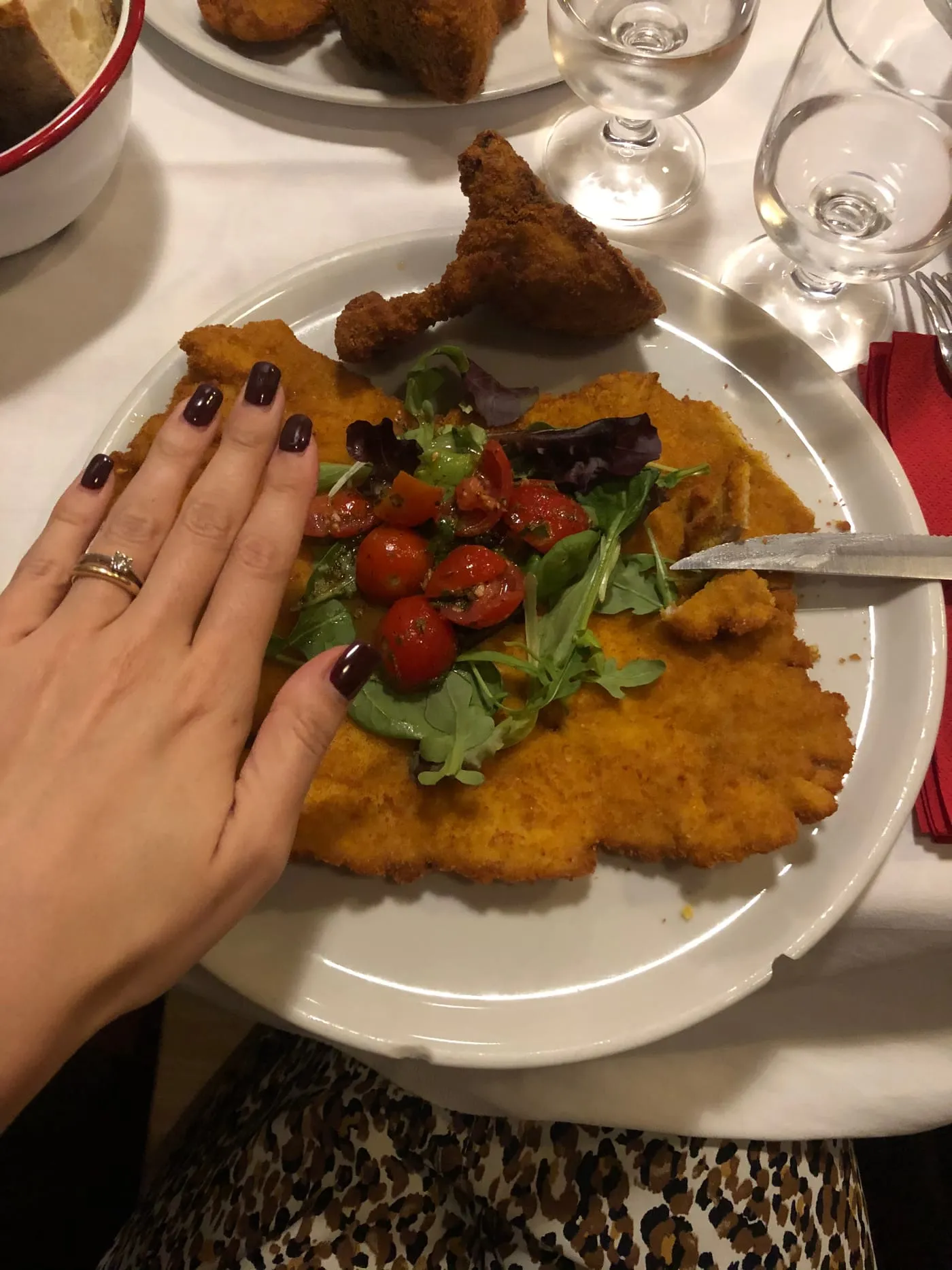 A cotoletta alla milanese as big as the plate, with salad leaves and cherry tomatoes in the middle