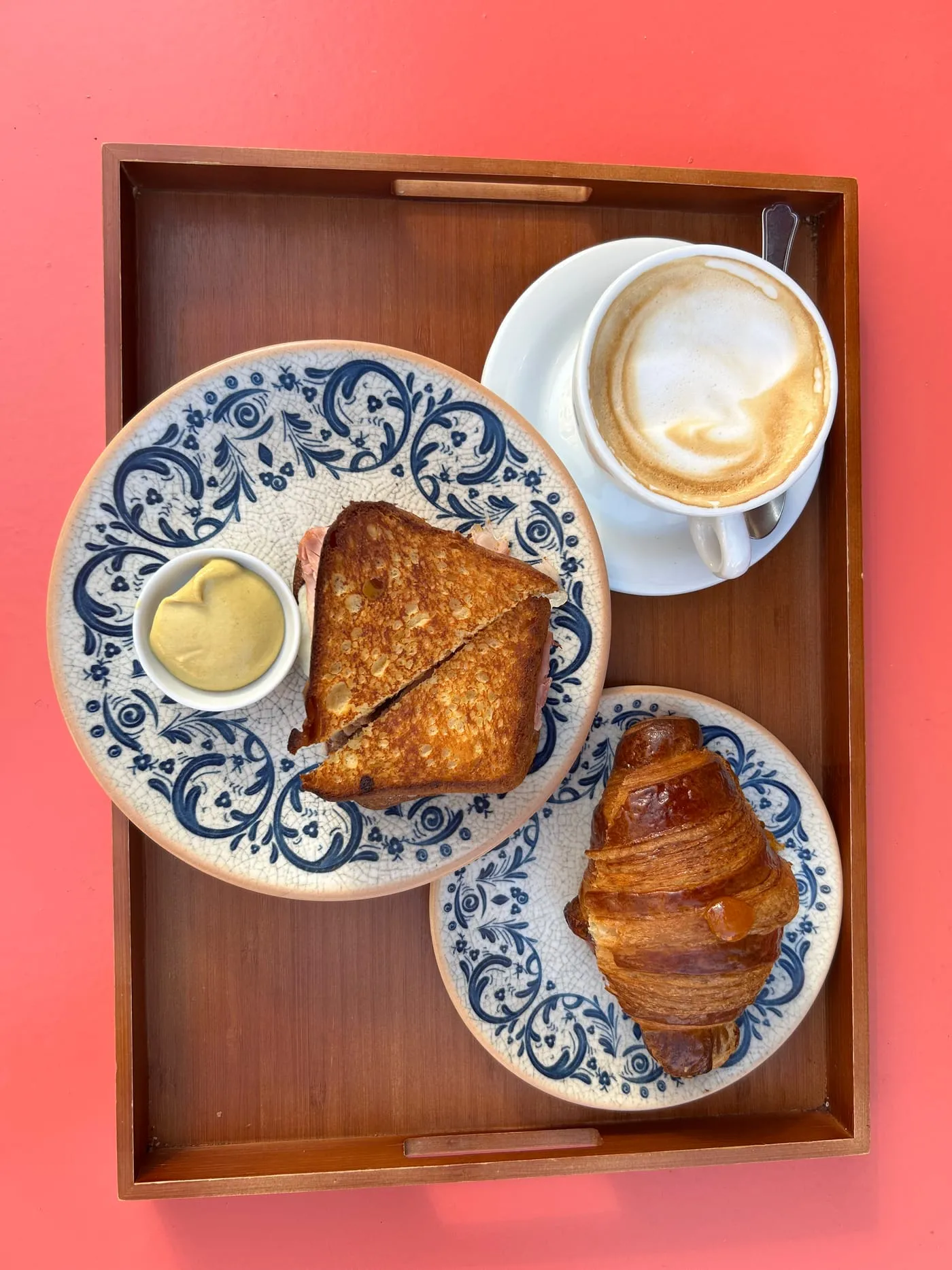 A tray with hot toast, a croissant and a cappuccino on blue-patterned plates