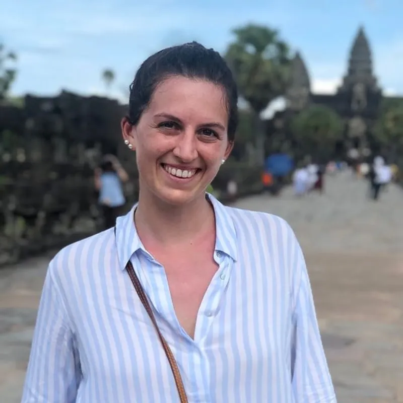 Giorgia standing and smiling, wearing a light blue striped shirt